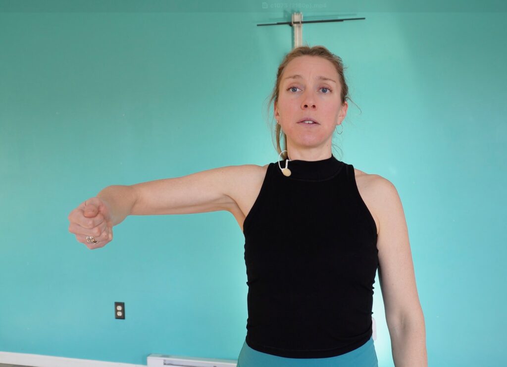 Dr. Chloe demonstrating the abduction exercise with her arm raised out to the side, palm facing up, and elbow and wrist in line